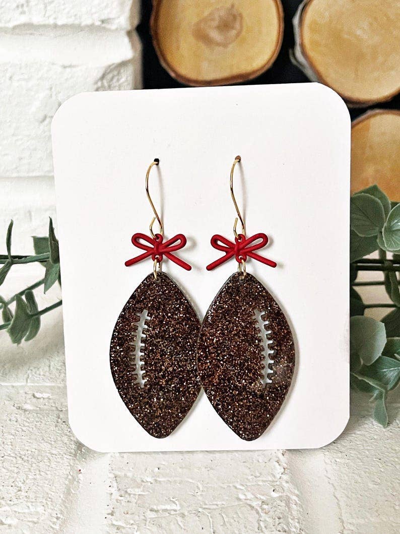 4186. Glitter Football Earrings: Game Day Sparkle with Red Bow