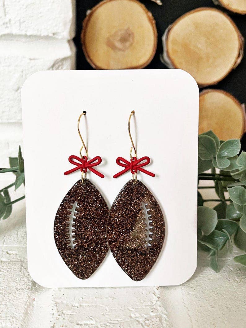 4186. Glitter Football Earrings: Game Day Sparkle with Red Bow